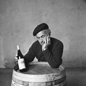 old black and white photo of mike looking at chardonnay bottle leaning on a barrel