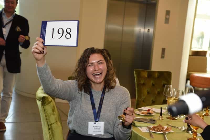woman holding up bidding number